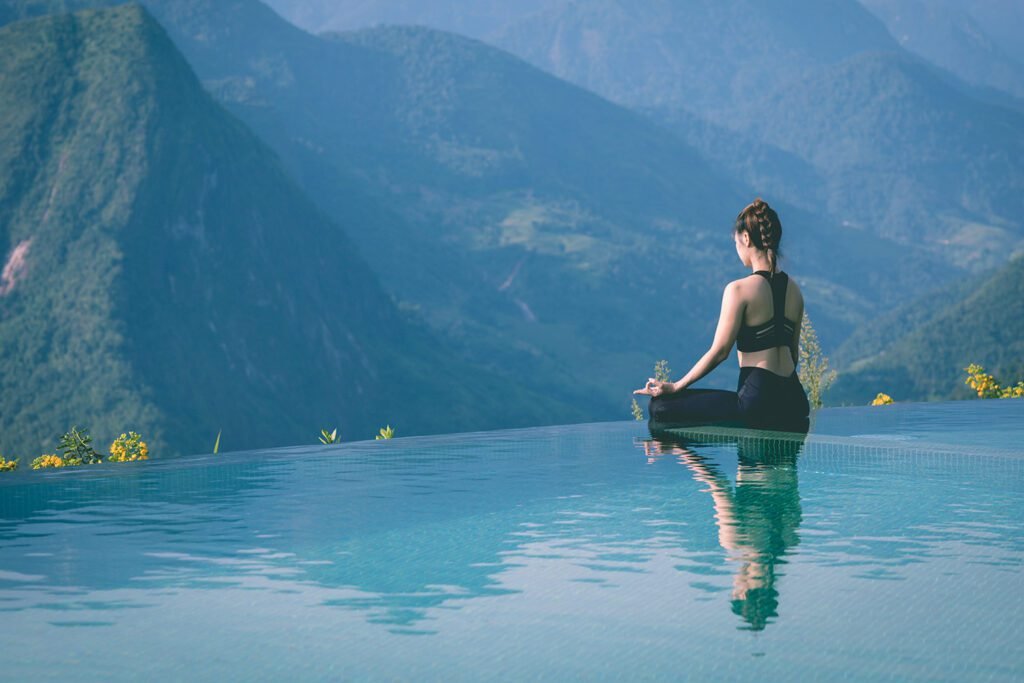 A young woman in a yoga pose with a scenic river view in the background, representing the 21-Day Yoga Challenge for Beginners