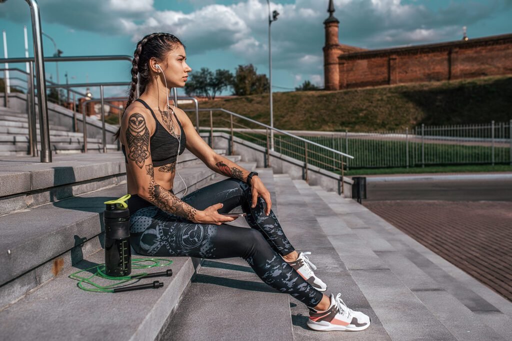 Preparing to get invigorated before working out, a girl is seen sitting on the stairs with a pre-workout drink bottle. How Long Does Pre-Workout Take to Kick In to Work?