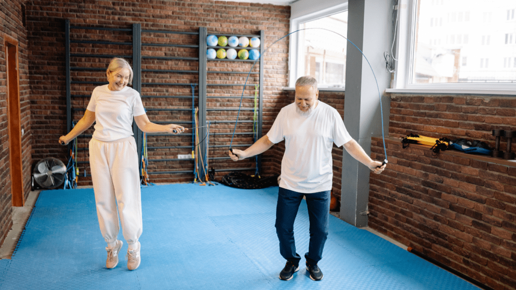Image of an older person joyfully participating in a jump rope workout session, guided by a fitness instructor. Demonstrating that jump rope workouts offer benefits for people of all ages.