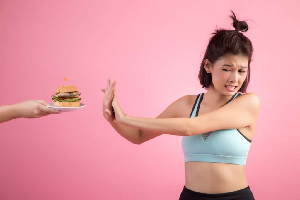 Asian woman refusing fast food with the text 'Knowing Why You Need to Lose Weight Quickly' highlighting the importance of informed choices.