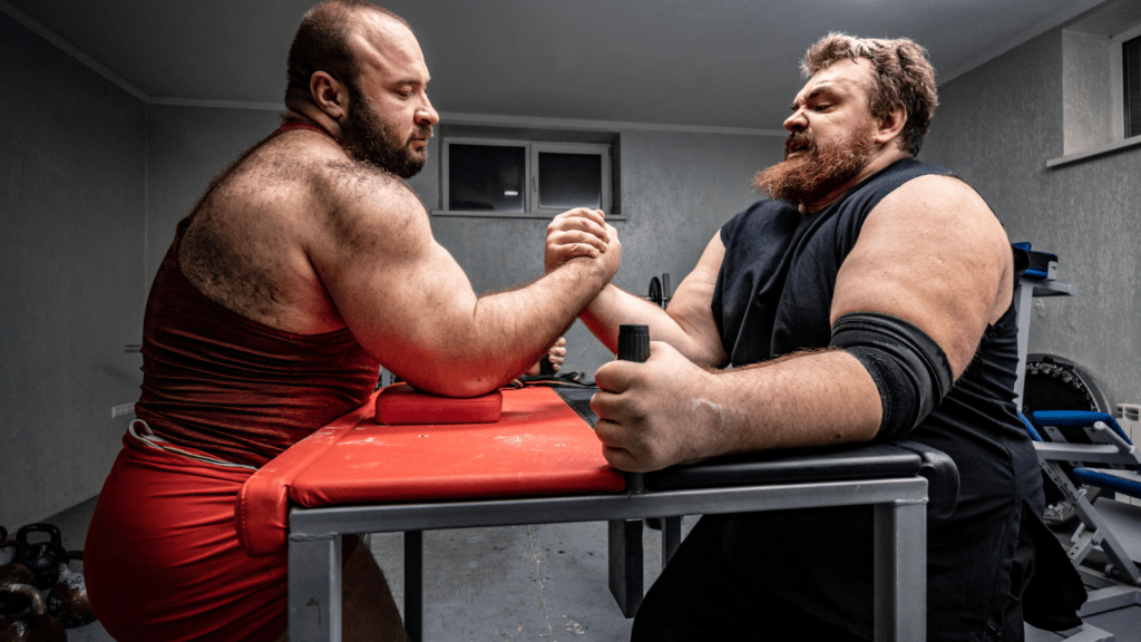 A picture of a Strength symbol and a cardio symbol engaged in an arm-wrestling match to show the differences between Strength and Cardio Training is used to get fit at home.