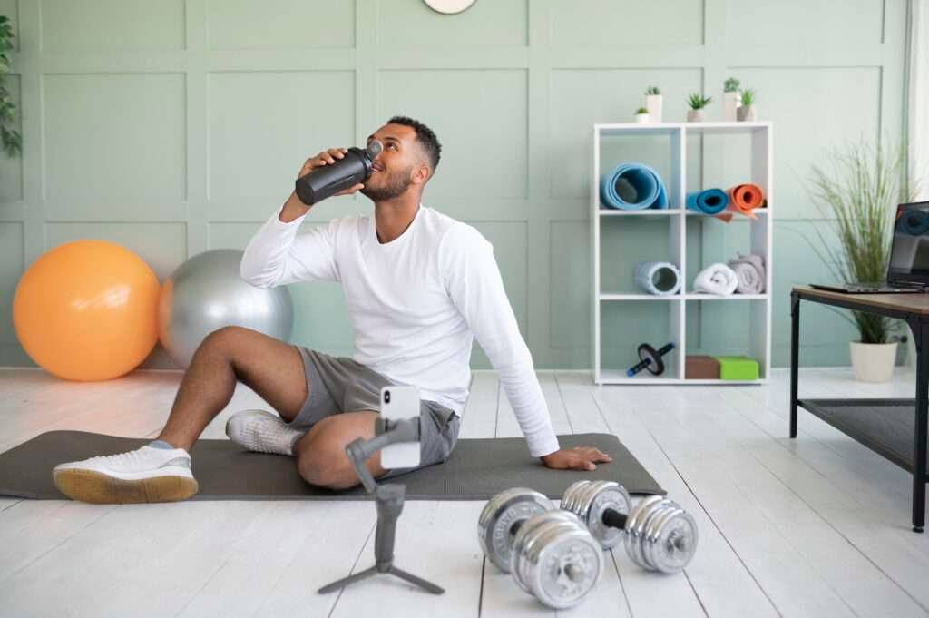 Full shot of a man drinking water, emphasizing the importance of balancing work and fitness while staying hydrated.